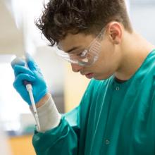 Student with safety glasses uses pipette in lab